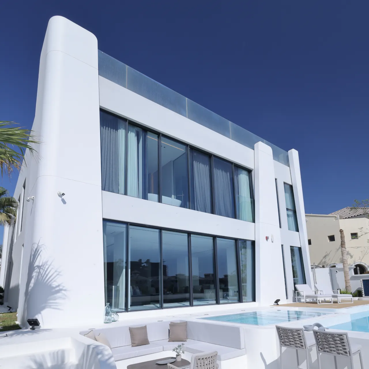 Modern exterior elevation design of a fully renovated house in Palm Jumeirah Dubai with stylish white facade and black framed large windows Modern exterior elevation design of a fully renovated house in Palm Jumeirah Dubai with stylish white facade and black framed large windows